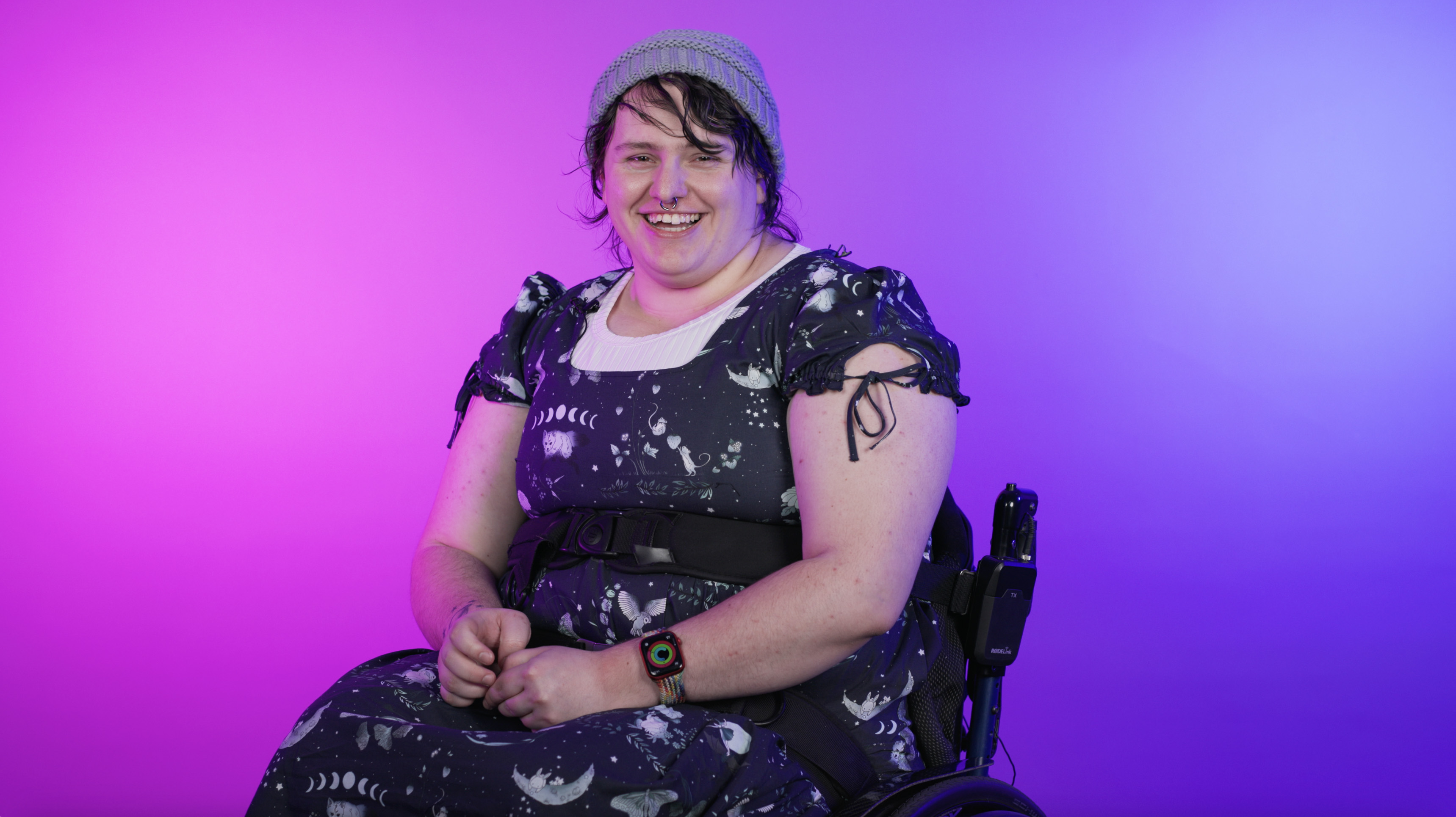 a young first nations person sits in their wheelchair, grinning at the camera